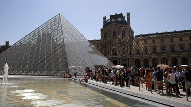 Los visitantes hacen cola en la entrada de la pirámide del museo del Louvre en París el 17 de junio de 2022.
