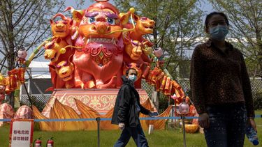 Residentes utilizan mascarillas para protegerse del coronavirus mientras caminan frente a esculturas en un parque de Wuhan, en la provincia de Hubei, en el centro de China, el jueves 9 de abril de 2020. 