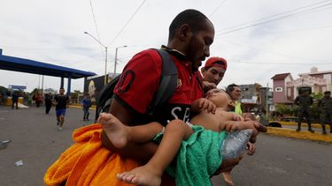 Un padre corre con su hija de un año herida hacia una ambulancia luego de enfrentamientos de migrantes con la Policía de Guatemala.&nbsp;