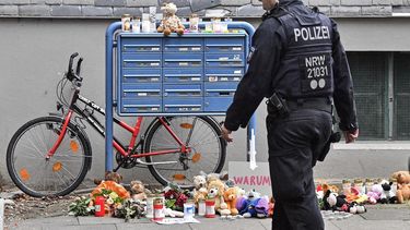 Un policía pasa frente a velas y osos de peluche en la entrada de una casa en donde cinco niños fueron encontrados muertos en Solingen, Alemania, el viernes 4 de septiembre de 2020.&nbsp;