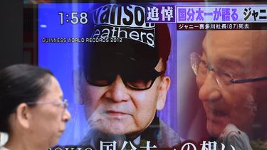 Una mujer pasa junto a una pantalla de televisión al borde de la carretera que informa sobre la muerte de Johnny Kitagawa, fundador de la agencia de talentos japonesa Johnny & Associates, en Tokio el 10 de julio de 2019.