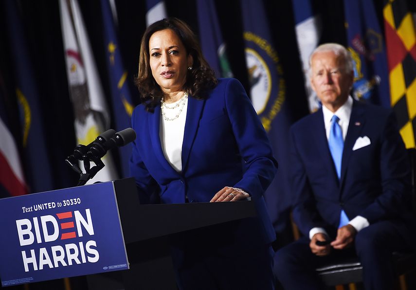 Kamala Harris habla a la audiencia, mientras Joe Biden observa atrás.