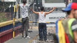 Dos venezolanos alzan sus manos mientras hablan a miembros de la Guardia Nacional Bolivariana que se encuentran en el lado venezolano del puente Francisco de Paula Santander en la frontera con Cúcuta, Colombia.