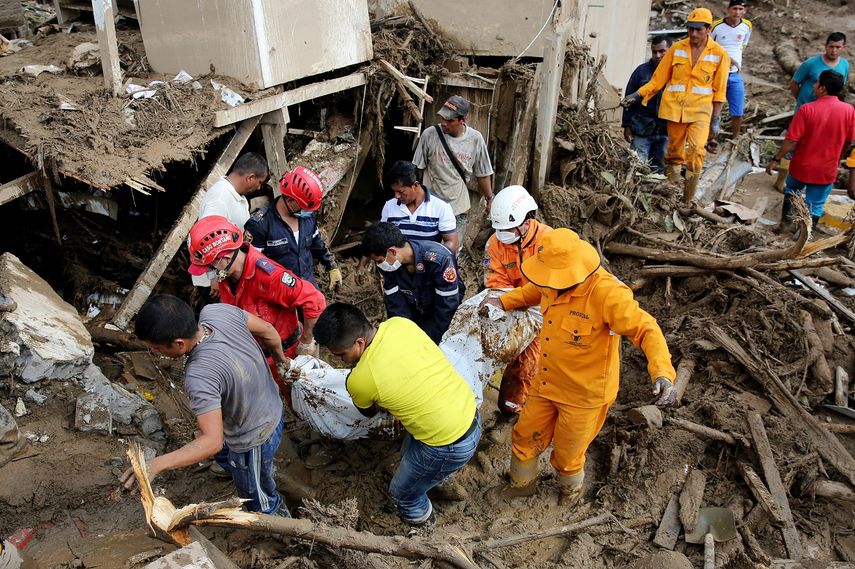 Miembros de los equipos de emergencia rescatan el cuerpo de una mujer, luego de una avalancha que afectó 17 barrios de la ciudad.