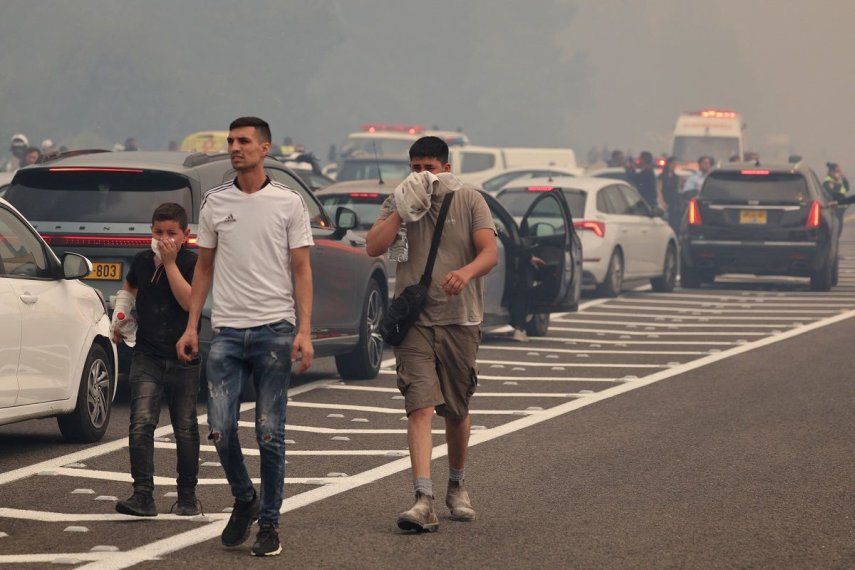 La gente camina por una autopista mientras los conductores se detienen durante un incendio forestal cerca de la ciudad de Bet Shemesh, en el centro de Israel, el 30 de abril de 2025.&nbsp;
