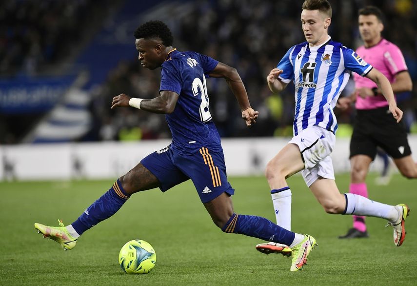 El extremo brasileño Vinícius Júnior, centro, del Real Madrid, avanza con el balón ante la marca del defensor Aihen Muñoz, de la Real Sociedad, en duelo de la Liga en el estadio Reale Arena de San Sebastián, España, el sábado 4 de diciembre de 2021.&nbsp;