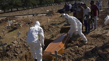 Empleados de un cementerio con trajes especiales para protegerse del coronavirus entierran el mi&eacute;rcoles 20 de mayo de 2020 a Amanda da Silva, de 22 a&ntilde;os, que falleci&oacute; de COVID-19, en el cementerio de Caju, en R&iacute;o de Janeiro.