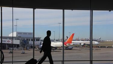 Un hombre camina junto a las ventanas de cristal de un aeropuerto.