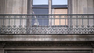 Una persona se encuentra detrás de la ventana por donde entraron los ladrones que robaron ocho valiosas joyas reales del Museo del Louvre, en París, el 20 de octubre de 2025.