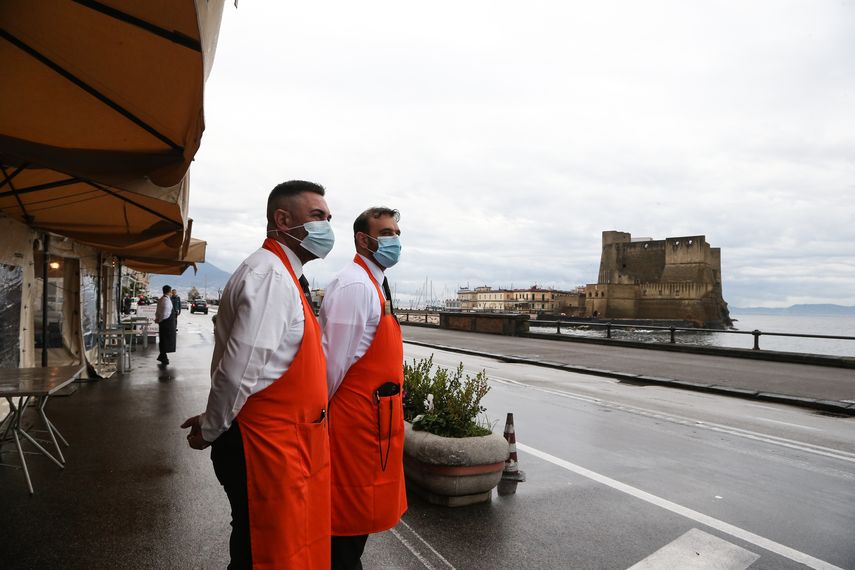 Dos empleados de un restaurante esperan por turistas en Nápoles, Italia.