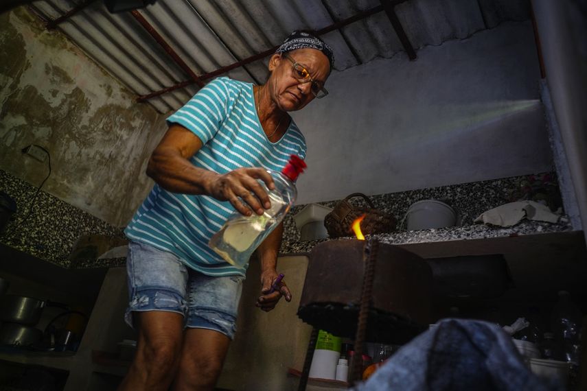 Rosa López enciende un horno a carbón para hervir boniatos y preparar huevos revueltos con tomate para sus nietos en su casa en Mariel, Cuba. 