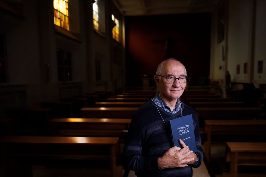 El diácono Jacques Beckand sostiene un libro utilizado durante las sesiones de exorcismo en el que se lee protección, liberación y curación mientras posa para una fotografía en una capilla del Hogar San José en Bruselas, el 11 de septiembre de 2024.&nbsp;