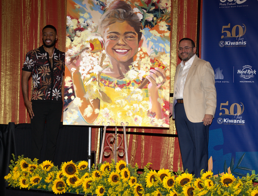 El autor del póster, el artista conocido como Mojo, posa junto a su obra, Our Heartbeat, y al presidente del Club de los Kiwanis de la Pequeña Habana, Pablo Lau.&nbsp;