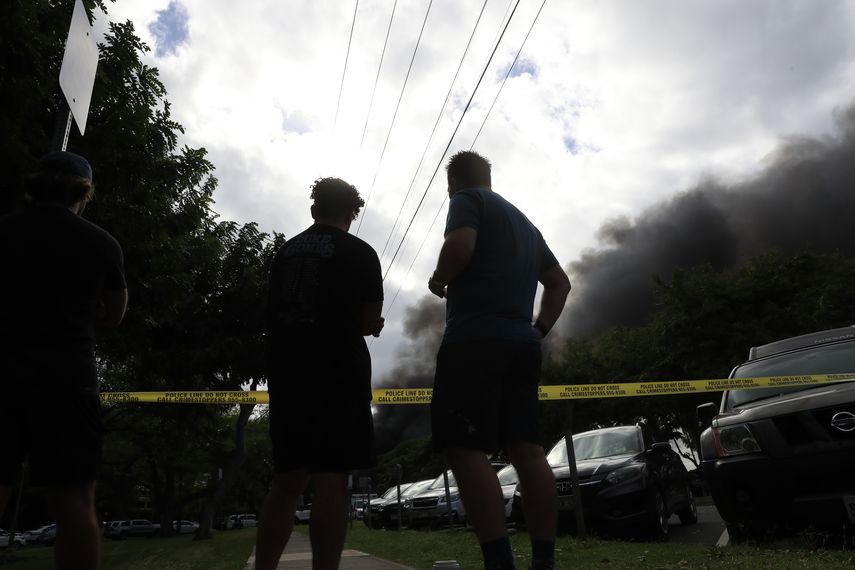 Transe&uacute;ntes observan el humo que sale de una casa incendiada despu&eacute;s de un tiroteo y una disputa dom&eacute;stica en una residencia de Hibiscus Road, cerca de Diamond Gead, el domingo 19 de enero de 2020, en Honolulu.&nbsp;