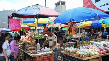 Una mujer compra comestibles, los carteles anuncian los precios en dólares en el mercado Quinta Crespo en Caracas el 20 de diciembre de 2022.