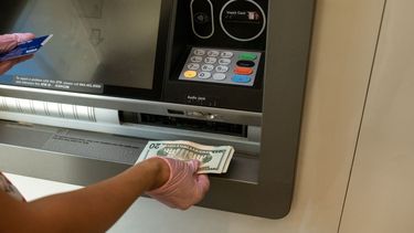 Un clientes extrae dinero de una cajero automático en un banco.