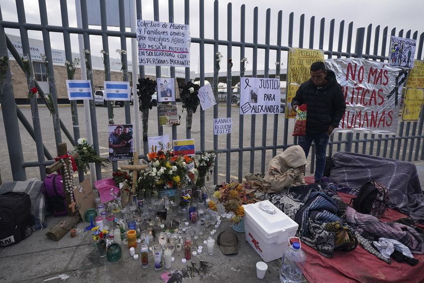 Un altar con velas y fotos cubre la cerca afuera del centro de detención de migrantes que fue el sitio de un incendio mortal, mientras los migrantes se despiertan después de pasar la noche en la acera en Ciudad Juárez, México, el jueves 30 de marzo de 2023.&nbsp;