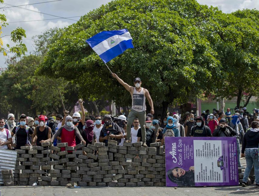 Un joven levanta una bandera de&nbsp;Nicaragua&nbsp;sobre una barricada de adoquines.&nbsp;