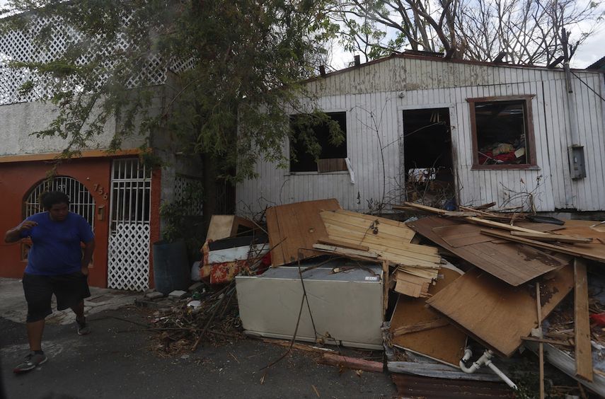 Un joven camina cerca a los escombros acumulados en la puerta de una casa causados por el paso del huracán María&nbsp; en el Barrio Obrero del distrito de Santurce, en&nbsp;San&nbsp;Juan&nbsp;(Puerto Rico).&nbsp;&nbsp;