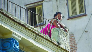 Una mujer habanera mira desde un balc&oacute;n.