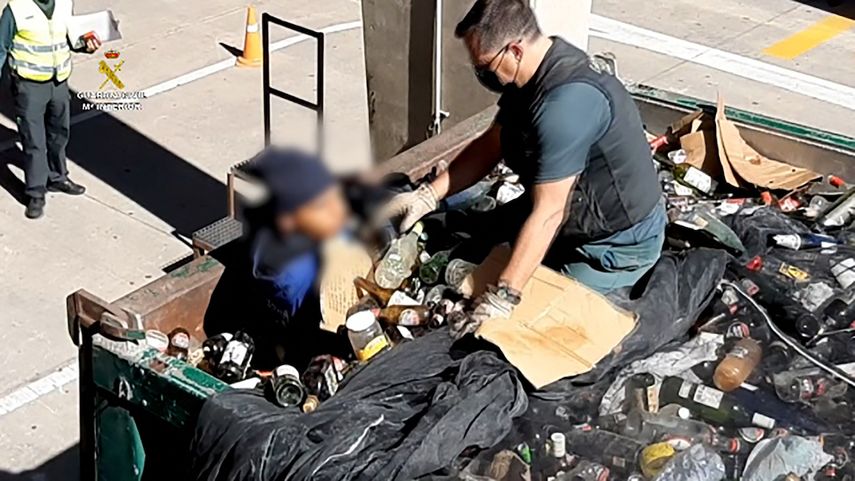 Una imagen publicada por la Guardia Civil española el 22 de febrero de 2021 muestra a un miembro de la Guardia Civil española descubriendo a un migrante escondido en un contenedor lleno de vidrios rotos para reciclar en el puerto del enclave español de Melilla en la costa norte de Marruecos, en febrero 19 de febrero de 2021.&nbsp;