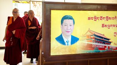 Varios monjes pasan junto a un retrato del presidente chino Xi Jinping