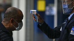 Un hombre se somete a un control de temperatura, instalado como medida para frenar el coronavirus COVID-19, a la entrada del centro comercial en Caracas, Venezuela.