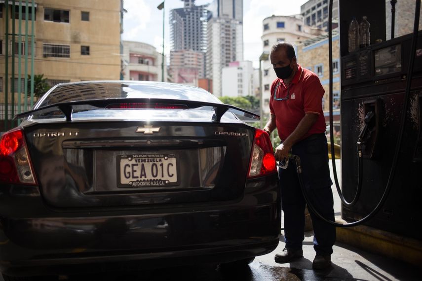 Un trabajador llena el tanque de un vehículo en una gasolinera de Caracas el 5 de octubre de 2020, en medio de la nueva pandemia de coronavirus. Venezuela lanzó este lunes un plan para distribuir gasolina según los números de matrícula de los vehículos, una medida en respuesta a la severa escasez de combustible en el país caribeño.