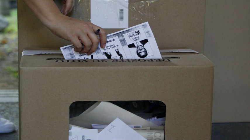Una mujer deposita en una urna la fotocopia del tarjetón de la consulta de la coalición de derecha&nbsp;
