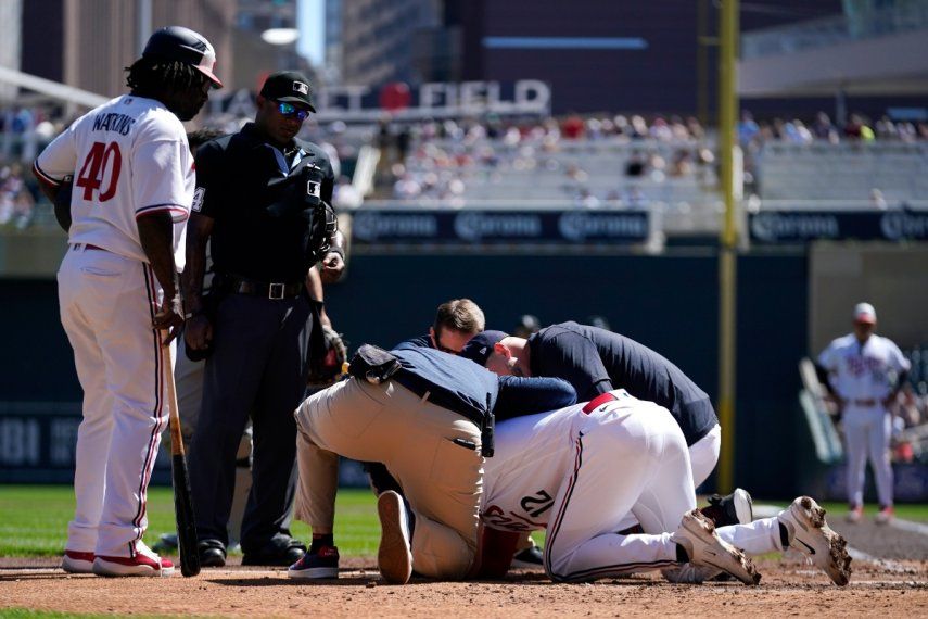 El jugador Kyle Farmer, de los Mellizos de Minnesota, es atendido después de haber sido golpeado en la cabeza por un lanzamiento durante la cuarta entrada del juego de béisbol en contra de los Medias Blancas de Chicago, el miércoles 12 de abril de 2023, en Minneapolis.