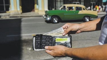 Un hombre muestra varios billetes de dólar en una calle en La Habana .