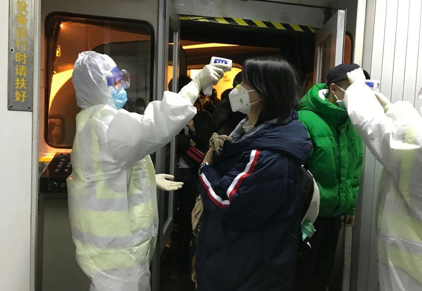 Funcionarios de salud revisan la temperatura corporal de los pasajeros que llegan de la ciudad de Wuhan al aeropuerto de Beijing, el mi&eacute;rcoles 22 de enero de 2020.