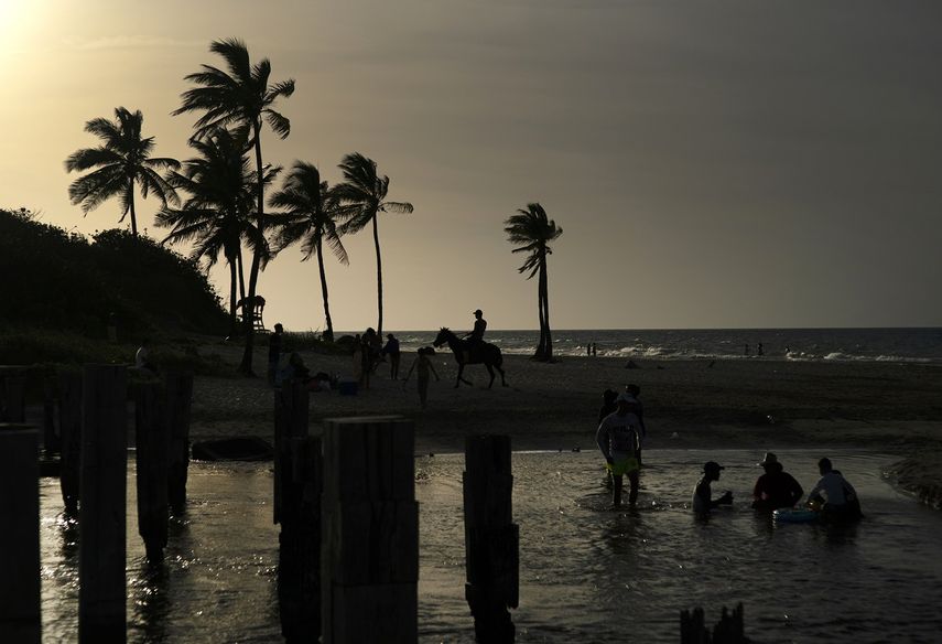 Un grupo de cubanos refresca en una playa del litoral norte de La Habana en un verano lleno de apagones y escaso de opciones recreativas.
