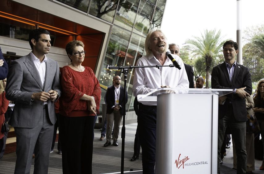Fotografía cedida por Brightline donde aparece el presidente del grupo Virgin, el millonario británico Richard Branson (c), mientras habla este jueves, junto al alcalde de Miami, Francis Suárez (i), y la comisionada, Rebeca Sosa, durante la ceremonia donde oficialmente la estación de la compañía Brightline pasó a llamarse Virgin MiamiCentral.