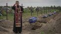 Un sacerdote ora por los restos de civiles no identificados antes de que sean enterrados el jueves 11 de agosto de 2022 en Bucha, en las afueras de Kiev, Ucrania. 