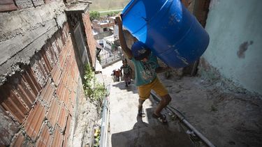Un niño sube unas escaleras cargado con dos recipientes vacíos que llenará con el agua suministrada por un camión cisterna del gobierno, en el vecindario de Petare, en Caracas, Venezuela, el 15 de junio de 2020. El colapso económico de Venezuela ha dejado a la mayoría de los hogares sin un suministro de agua corriente confiable. 