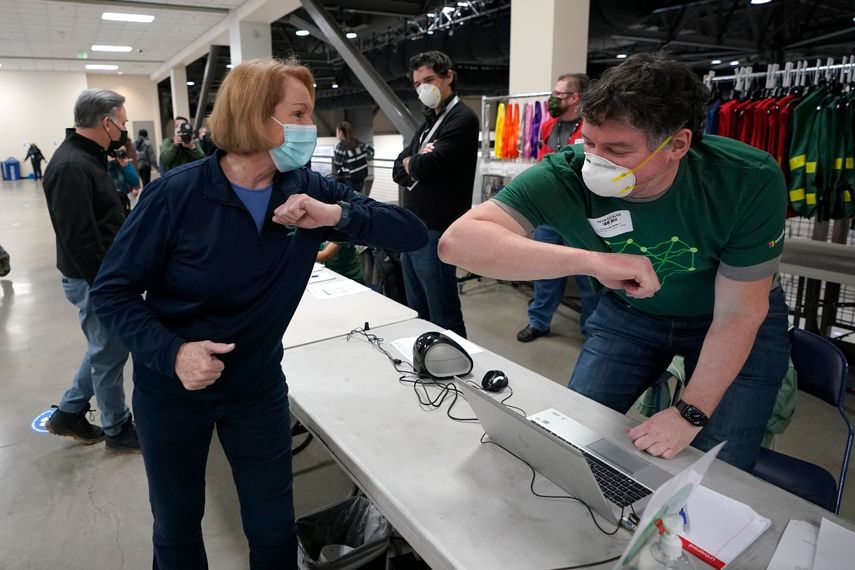En esta fotografía del 13 de marzo de 2021, la alcaldesa de Seattle, Jenny Durkan, saluda a un trabajador en un centro de vacunación, en Seattle, Washington.