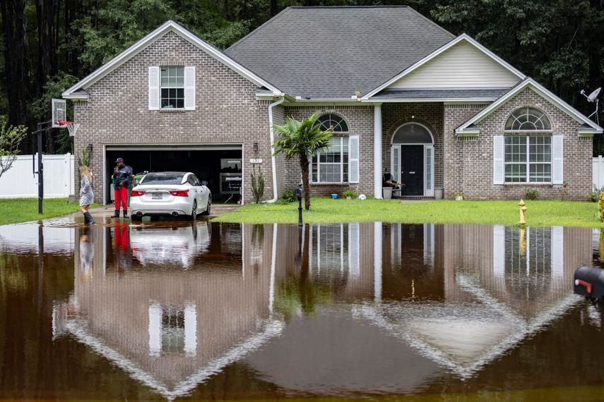 Keon Johnson y su esposa, Zyla Johnson, a la izquierda, hablan sobre cómo llegar a trabajar dado que su casa se ha inundado por las lluvias de la tormenta tropical Debby, el miércoles 7 de agosto de 2024 en Pooler, Georgia. &nbsp;