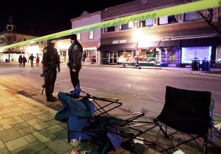 Policías montan guardia cerca de sillas derribadas a lo largo de W. Main St., el domingo 21 de noviembre de 2021, en Waukesha, Wisconsin, después de que una camioneta embistió un desfile navideño, donde murieron 5 personas y otras cuantas quedaron heridas. 