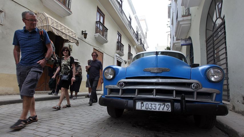 Turistas caminan junto a un auto clásico en La Habana, Cuba.&nbsp;
