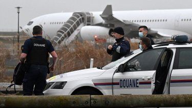 Los agentes de aduanas franceses se encuentran junto cerca del Airbus A340 que estuvo parado en la pista desde el 21 de diciembre por sospecha de tráfico de personas, en el aeropuerto de Vatry, en el noreste de Francia, el 25 de diciembre de 2023.