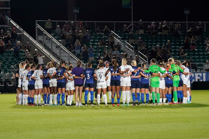 Jugadoras del Courage de Carolina del Norte y del Racing de Louisville se reúnen a la mitad del campo durante la primera mitad del partido de la NWSL