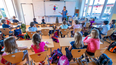 Una maestra en el salón de clases con sus alumnos tras regreso de vacaciones.