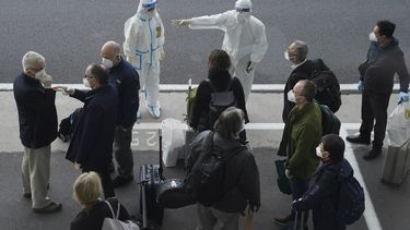 Un trabajador, equipado con un traje de protección, dirige a los miembros de un equipo de expertos de la Organización Mundial de la Salud a su llegada al aeropuerto de Wuhan, en la provincia de Hubei, en China, el 14 de enero de 2021.