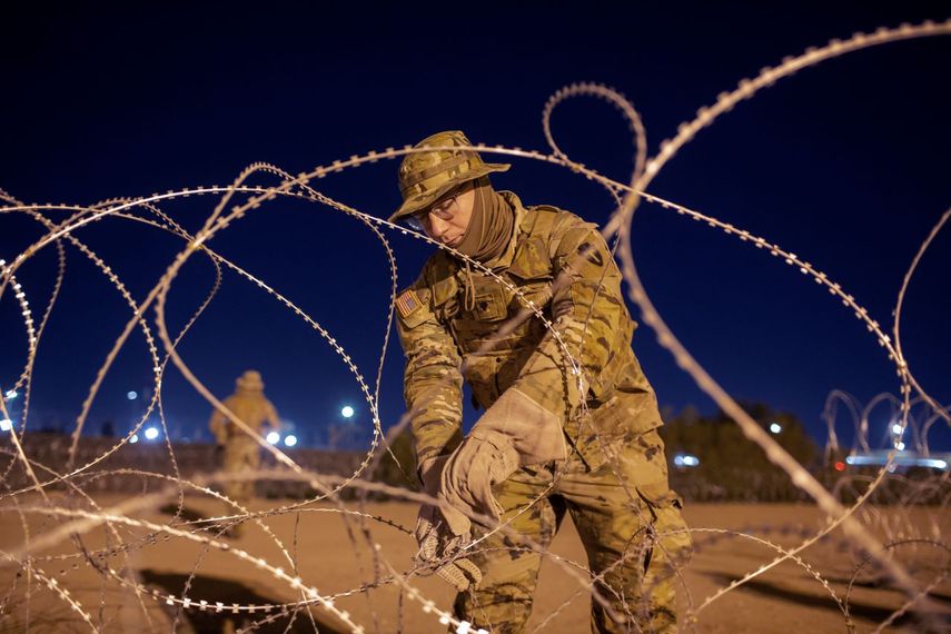 Un soldado de la Guardia Nacional de Texas amarra hileras de alambre de púas que será instalado cerca de una entrada en la valla fronteriza, en El Paso, Texas. 