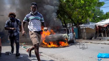 Unas personas se alejan de un automóvil en llamas durante una protesta el lunes 5 de octubre de 2020 en Puerto Príncipe, para exigir justicia por la muerte de un manifestante que fue baleado por la policía la semana pasada.