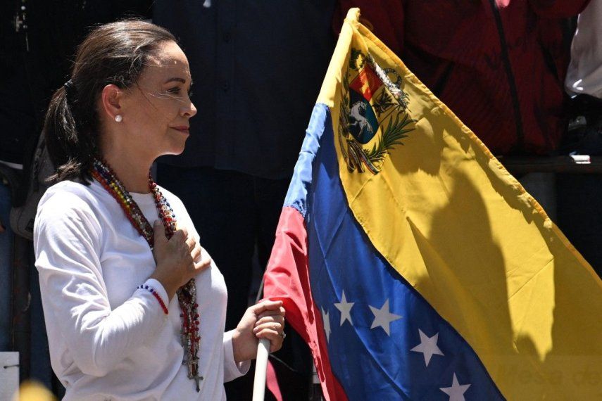 La líder opositora venezolana María Corina Machado sostiene una bandera nacional venezolana mientras hace un gesto desde lo alto de un camión durante una manifestación para protestar por los resultados de las elecciones presidenciales, en Caracas el 3 de agosto de 2024.&nbsp;