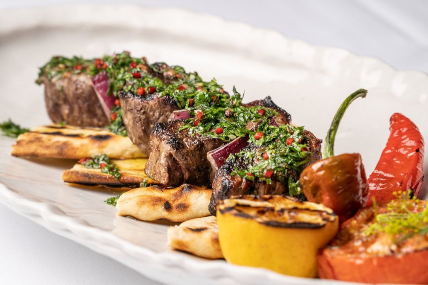Souvlaki de filete mignon con tomate y pimientos asados al roble, cubierto con salsa verde.&nbsp;