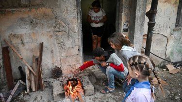 Un hombre cocina salchichas sobre un fuego de leña junto a su esposa e hijas durante un corte de electricidad en el barrio de Poey en La Habana.