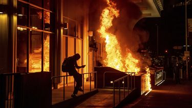 Manifestantes prenden fuego al frente del edificio de California Bank y Trust durante una protesta contra la brutalidad policial en Oakland, California, la noche del viernes 16 de abril de 2021.&nbsp;